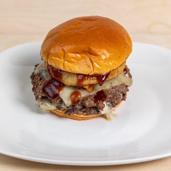 A Townline Grill burger with two patties, melted cheese, onion rings, and BBQ sauce.
